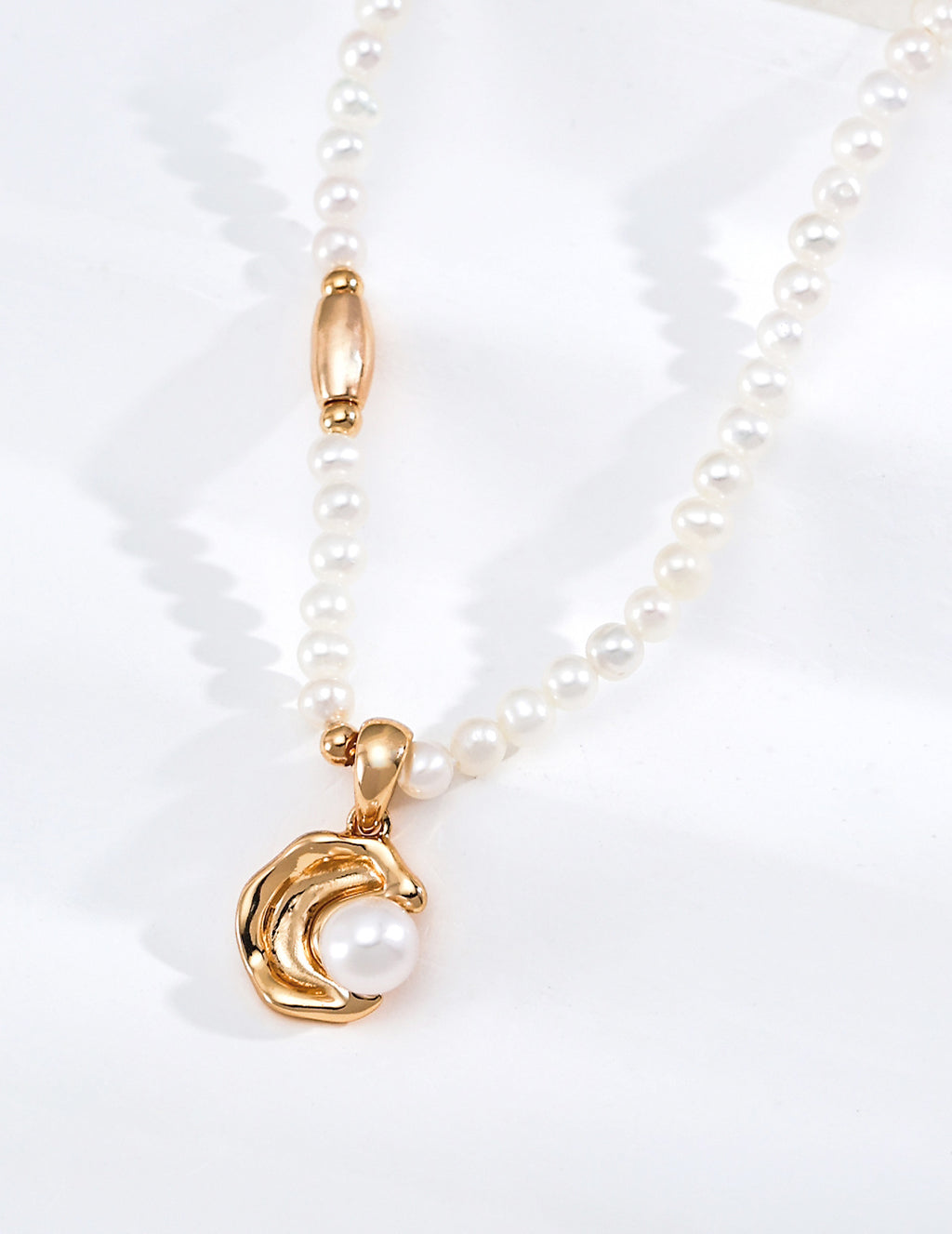 Close view of the Vintage Pearl necklace in vintage gold, showing a curved pendant framing a pearl
