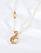 Close view of the Vintage Pearl necklace in vintage gold, showing a curved pendant framing a pearl
