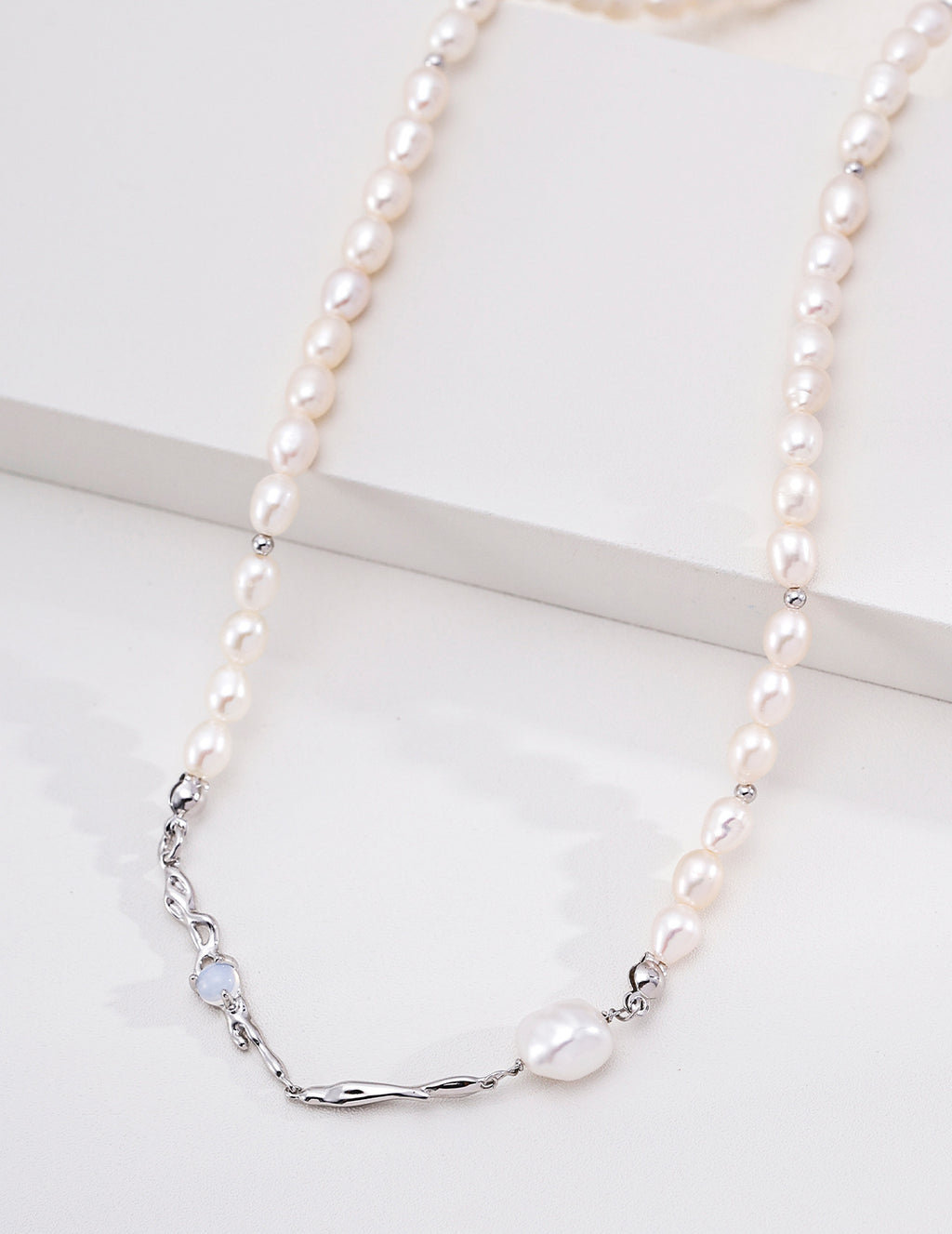Close view of the platinum silver Liquid Metal pearl necklace, showing flowing metal accents on a white display