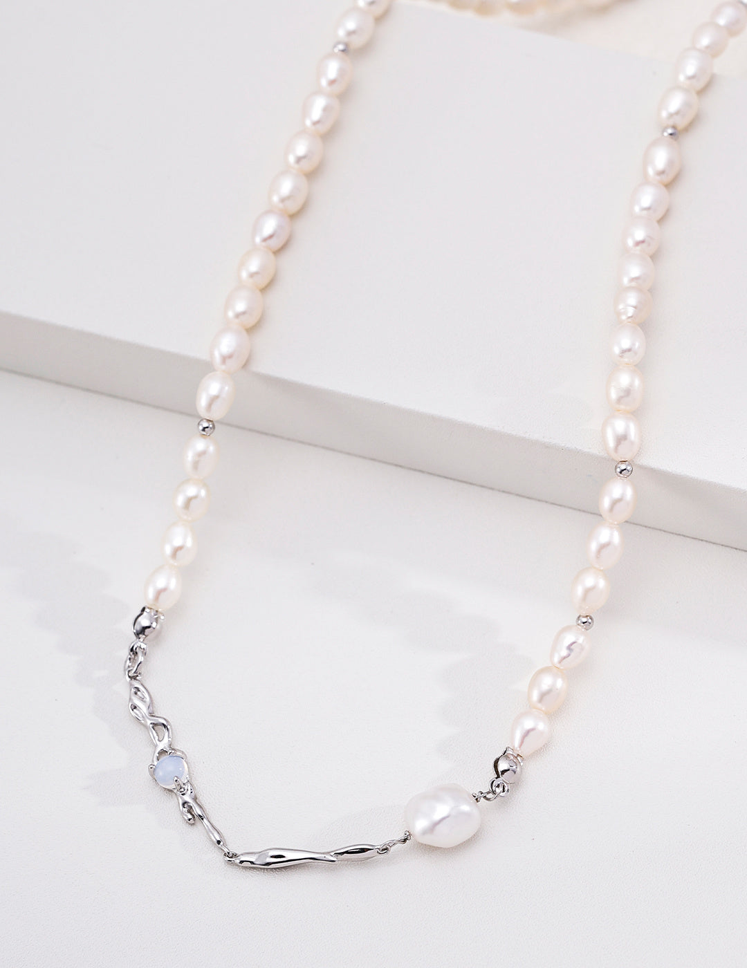 Close view of the platinum silver Liquid Metal pearl necklace, showing flowing metal accents on a white display