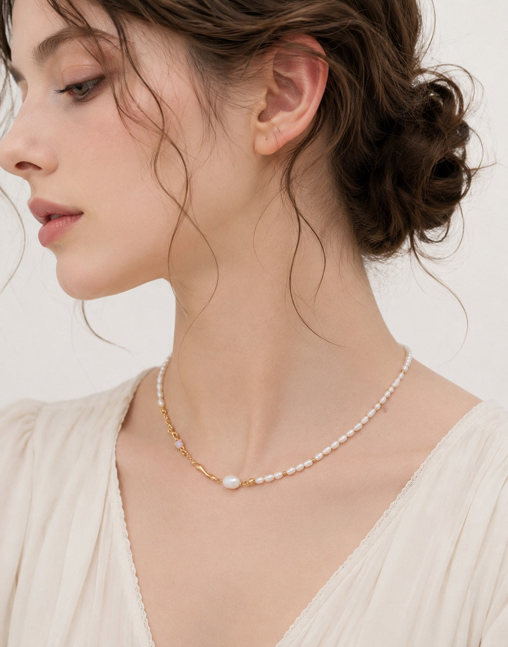 Liquid Metal pearl necklace in vintage gold worn with a cream blouse, showing the sculpted accents at the neckline