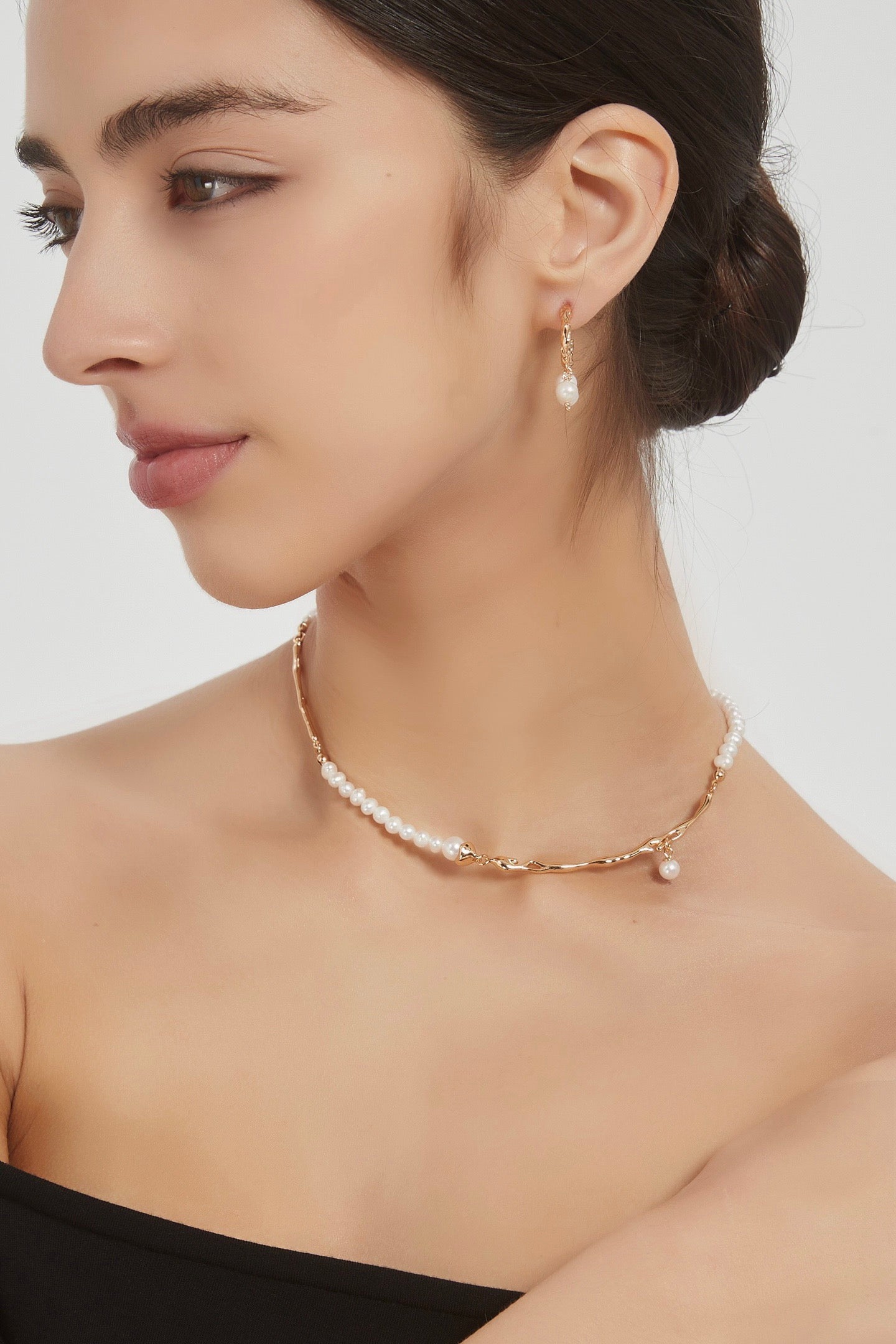Geometric Baroque pearl necklace in vintage gold worn with a black top, showing metal accents and a small pearl drop