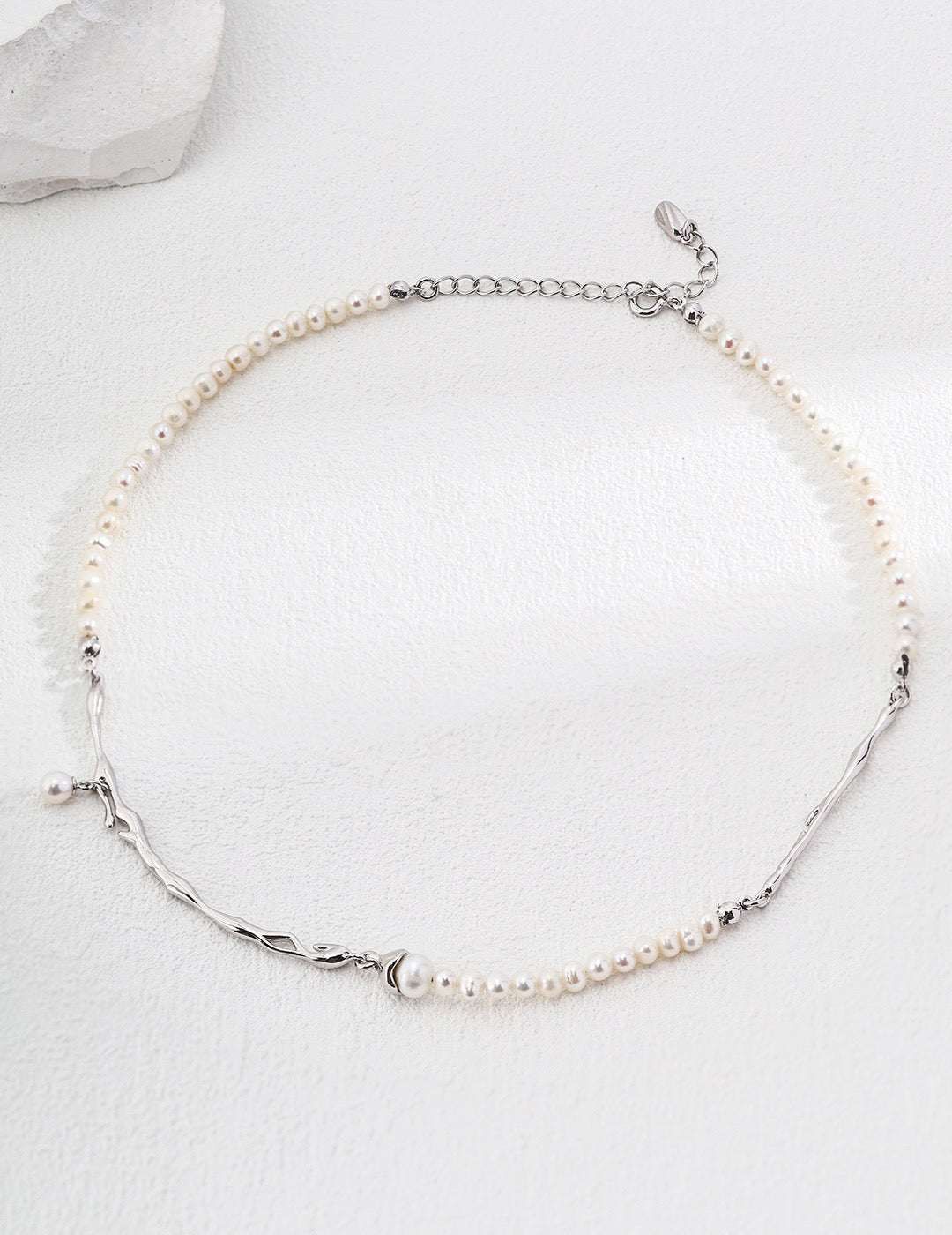 Geometric Baroque pearl necklace in platinum silver arranged in a circle, with irregular metal accents and an extension chain