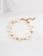 Baroque pearl bracelet in vintage gold arranged on a white surface, with irregular pearls and rounded gold accents