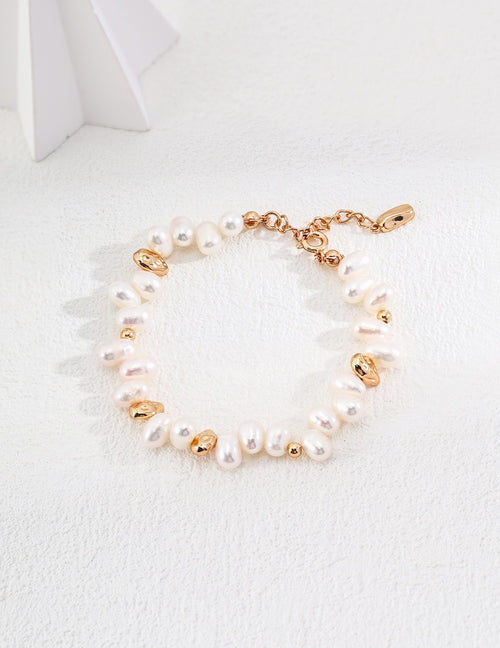 Baroque pearl bracelet in vintage gold arranged on a white surface, with irregular pearls and rounded gold accents