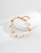 Baroque pearl bracelet in vintage gold resting against a white stone, showing pearl shapes, gold accents and the extension chain