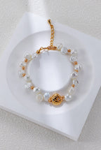 Baroque pearl bracelet in vintage gold on a white display, with round spacers and a textured centerpiece