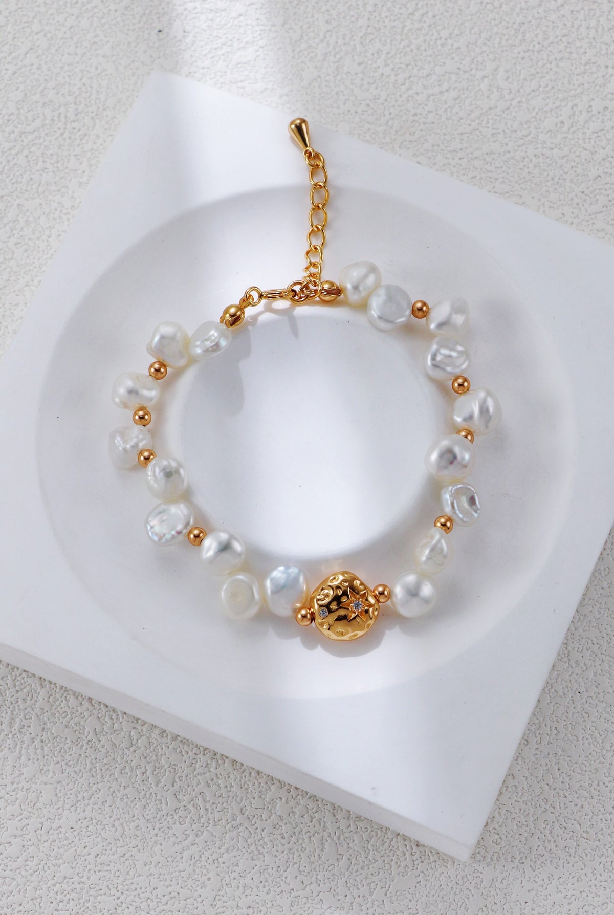 Baroque pearl bracelet in vintage gold on a white display, with round spacers and a textured centerpiece