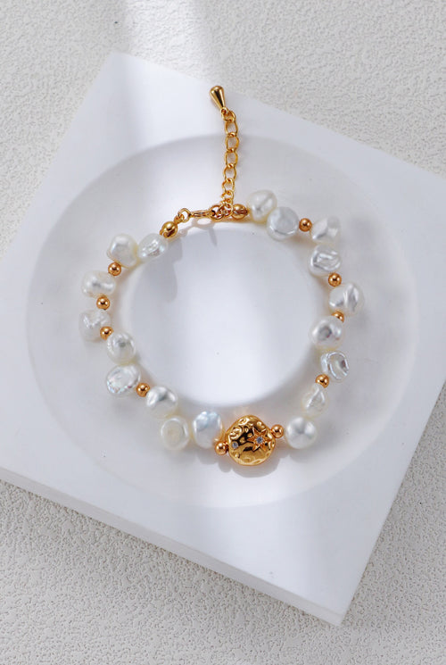 Baroque pearl bracelet in vintage gold on a white display, with round spacers and a textured centerpiece