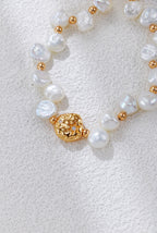 Close view of the Celestial Charm pearl bracelet in vintage gold, showing the textured round centerpiece and irregular pearls