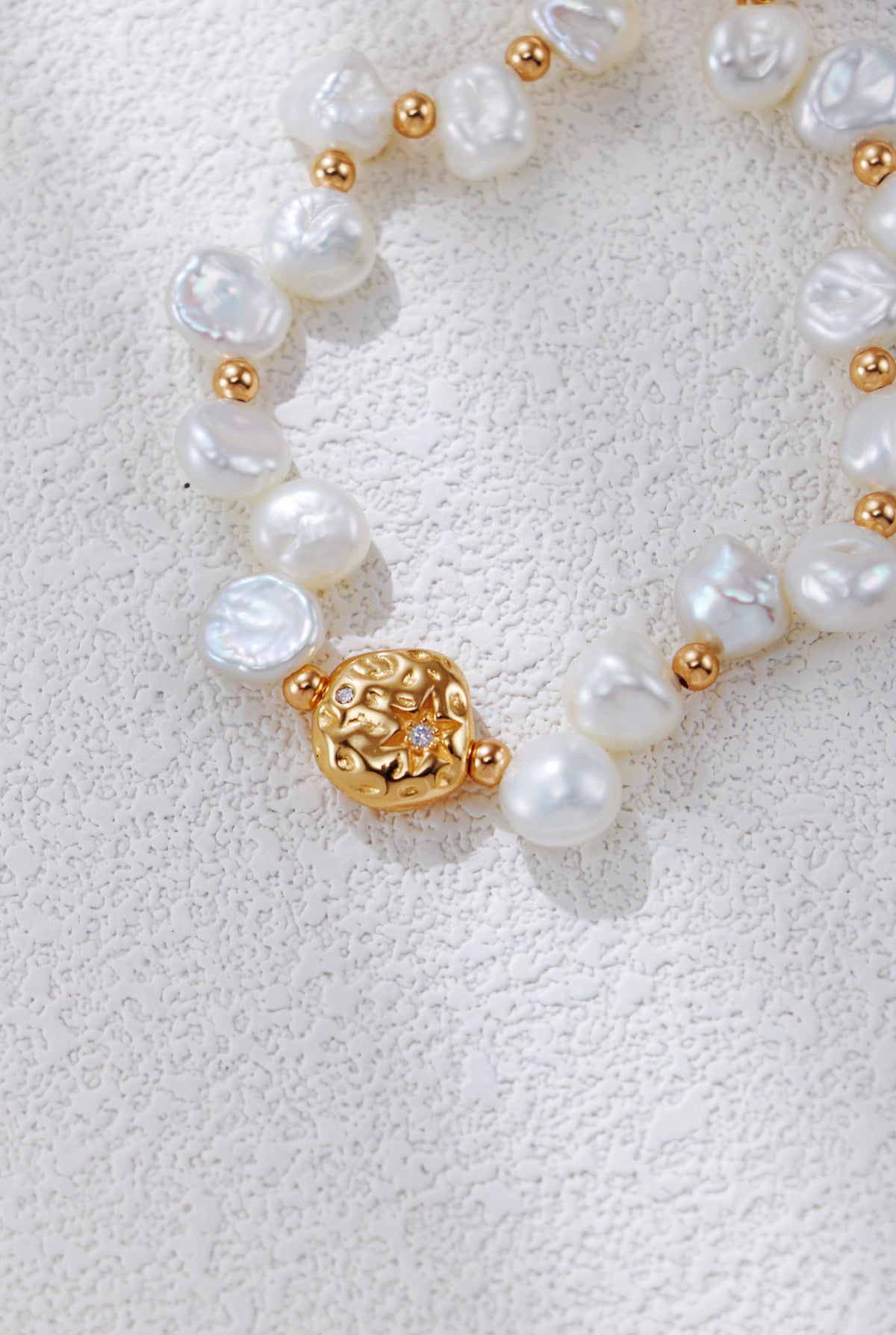 Close view of the Celestial Charm pearl bracelet in vintage gold, showing the textured round centerpiece and irregular pearls