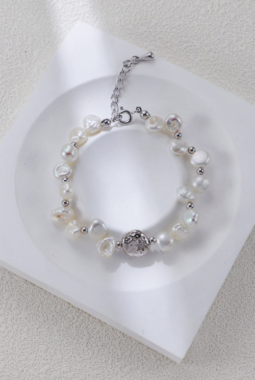 Celestial Charm pearl bracelet in platinum silver on a white display, with round spacers and a textured centerpiece