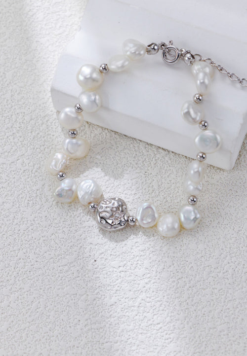 Close view of the Celestial Charm pearl bracelet in platinum silver, with irregular pearls and a textured round centerpiece