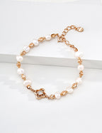 Lustrous pearl bracelet with vintage gold spacers and a four-lobed centerpiece, displayed on a white block