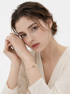 Lustrous pearl bracelet with a vintage gold four-lobed centerpiece worn at the wrist with a cream blouse