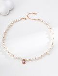 Baroque pearl necklace arranged in a circle, with vintage gold spacers and a pink crystal pendant at the center