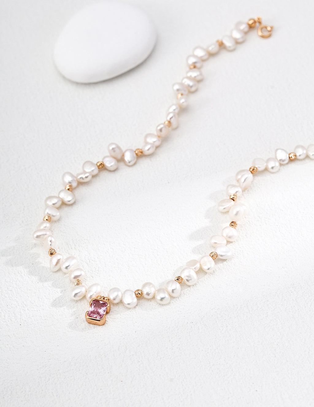 Close view of the Baroque Pearl and Pink Crystal pendant necklace, showing the pink centerpiece and vintage gold spacers