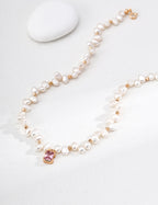 Close view of the Baroque Pearl and Pink Crystal pendant necklace, showing the pink centerpiece and vintage gold spacers