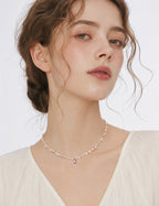 Baroque pearl necklace with a pink crystal pendant worn with a cream V-neck blouse