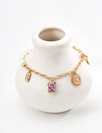 Enchanted Pink Charm pearl bracelet around a white ceramic vase, showing a pink crystal pendant and vintage gold charms